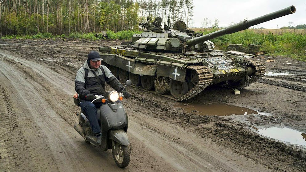 Ein Rollerfahrer passiert im September 2022 bei der ukrainischen Stadt Isjum einen zerstörten russischen Panzer.