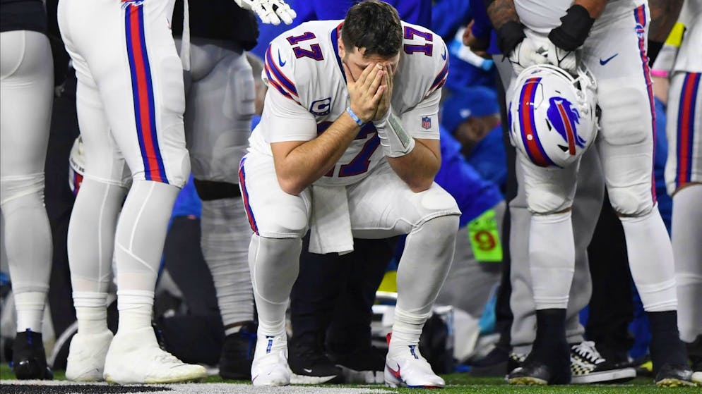 Quarterback Josh Allen von den Buffalo Bills hält inne, während Damar Hamlin vom medizinischen Personal untersucht wird.