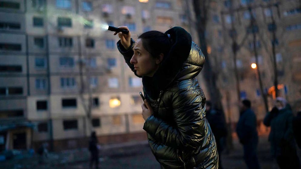 Nadiia Yaroshenko versucht ihre Katze mit einer Taschenlampe zu finden, die in einem beschädigten Gebäude in Dnipro eingeschlossen ist. Foto: Roman Hrytsyna/AP/dpa