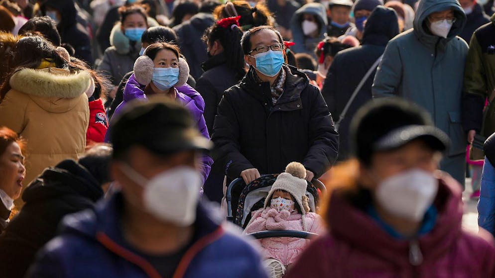 Besucher mit Gesichtsmasken spazieren am ersten Tag des Mondneujahrsfestes in Peking durch die Fußgängerzone Qianmen. Foto: Andy Wong/AP/dpa