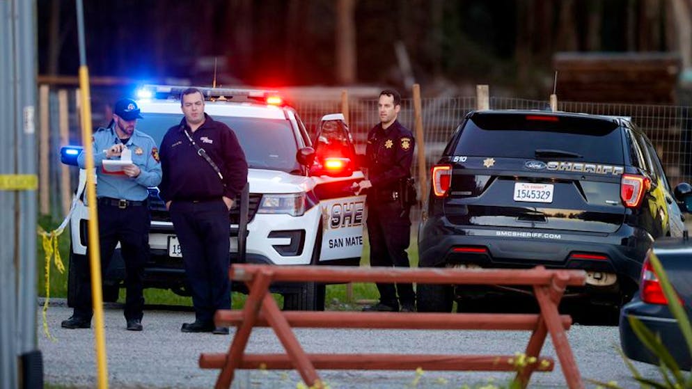 Beamte des San Mateo County Sheriffs und Mitarbeiter des Rettungsdienstes versammeln sich entlang einer Strasse in der Nähe des Ortes, an dem mehrere Menschen erschossen aufgefunden wurden.