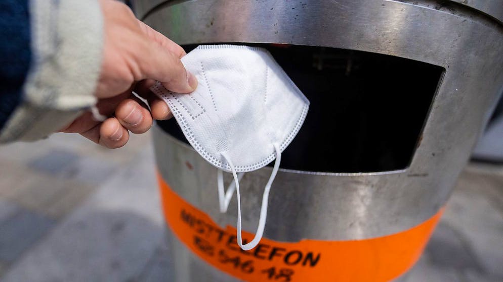 ARCHIV - Eine FFP2-Maske wird in Wien in einen Abfalleimer geworfen. Foto: Georg Hochmuth/APA/dpa