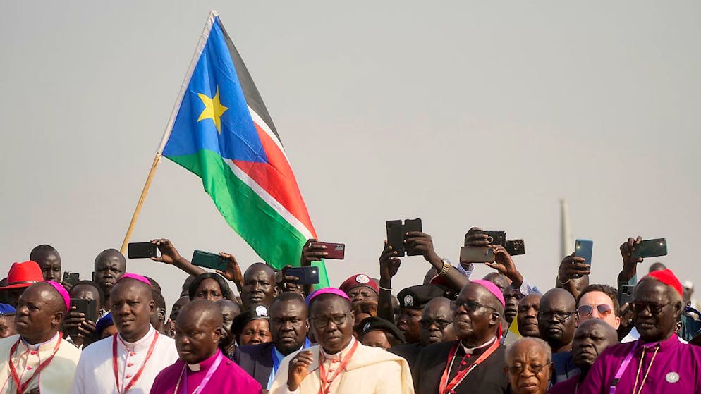 Menschen warten mit ihren Handys in der Hand auf die Ankunft von Papst Franziskus am Flughafen von Juba. Foto: Gregorio Borgia/AP/dpa