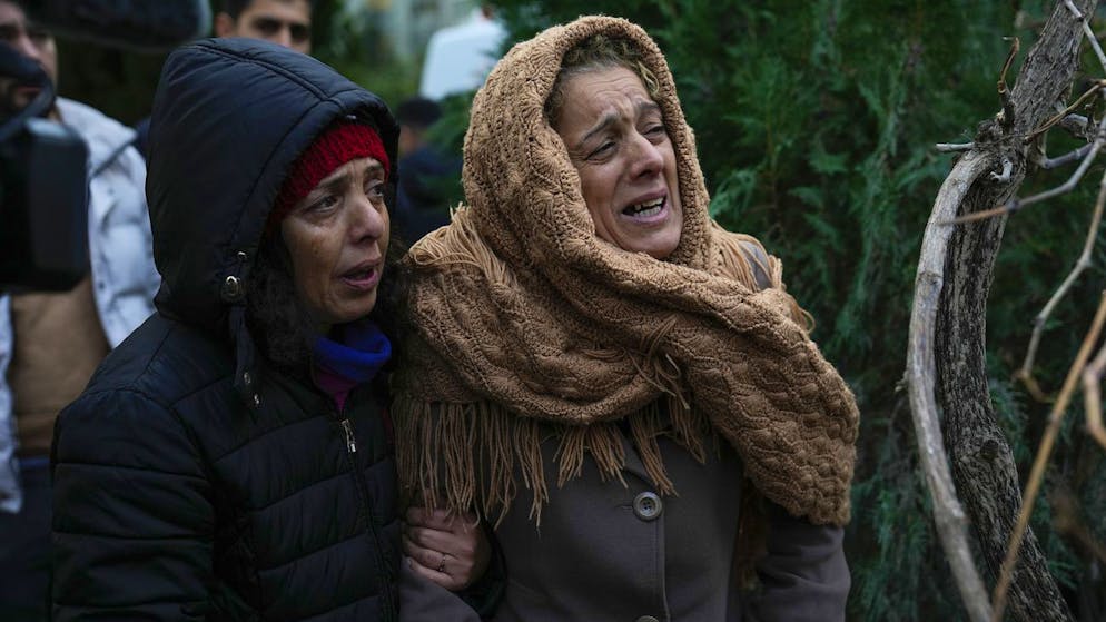 Erdbeben in der Türkei und in Syrien. <strong>6. Februar, Türkei:</strong> Frauen weinen, während sie zusehen, wie die Rettungskräfte in den Trümmern eines zerstörten Gebäudes in Adana nach Menschen suchen.