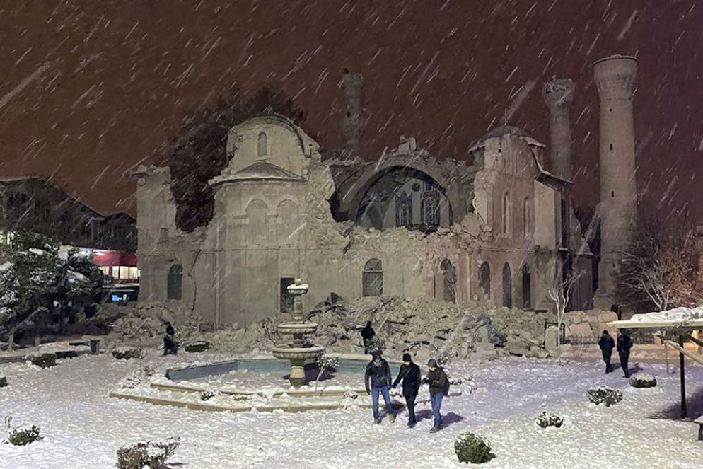 Des gens marchent à côté d'une mosquée détruite par un tremblement de terre à Malatya, en Turquie, le lundi 6 février 2023.