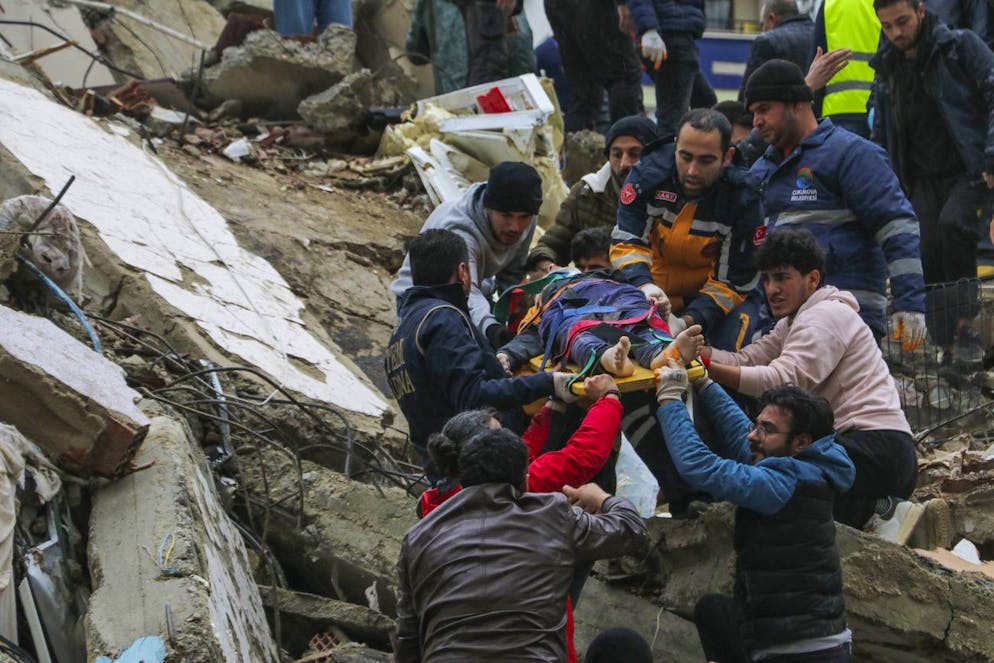 Des personnes et des équipes d'urgence sauvent une personne sur une civière d'un bâtiment effondré à Adana, en Turquie, le lundi 6 février 2023.