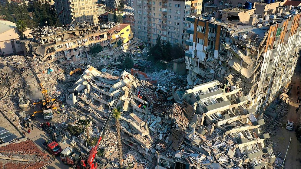 Rettungsteams suchen nach Menschen, während Kräne Trümmer von zerstörten Gebäuden entfernen. Foto: Hussein Malla/AP/dpa