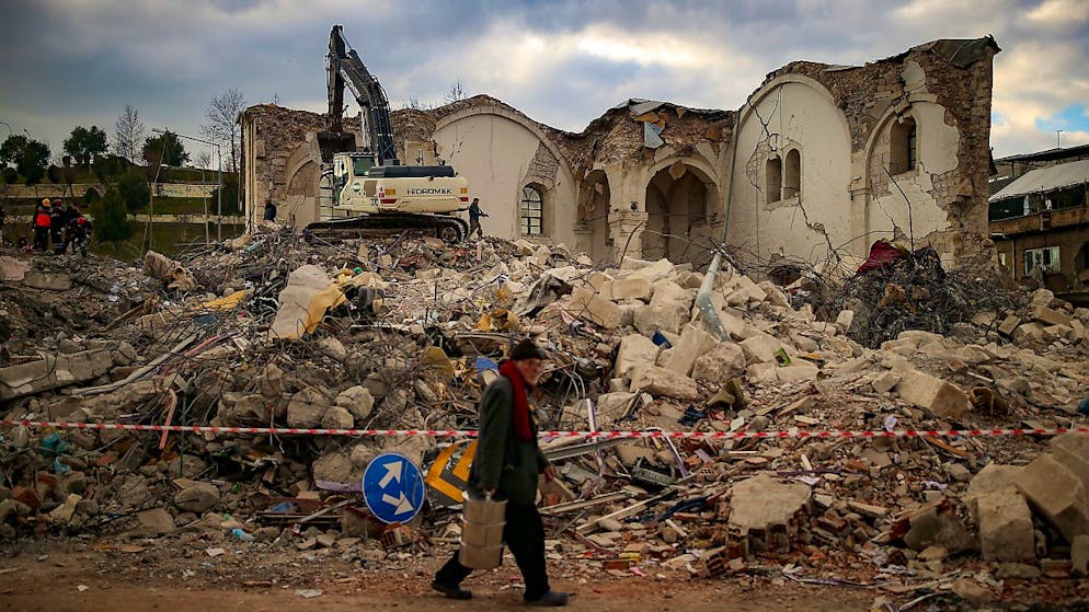 Ein Mann geht an einem eingestürzten Gebäude in Adiyaman vorbei. Foto: Emrah Gurel/AP/dpa