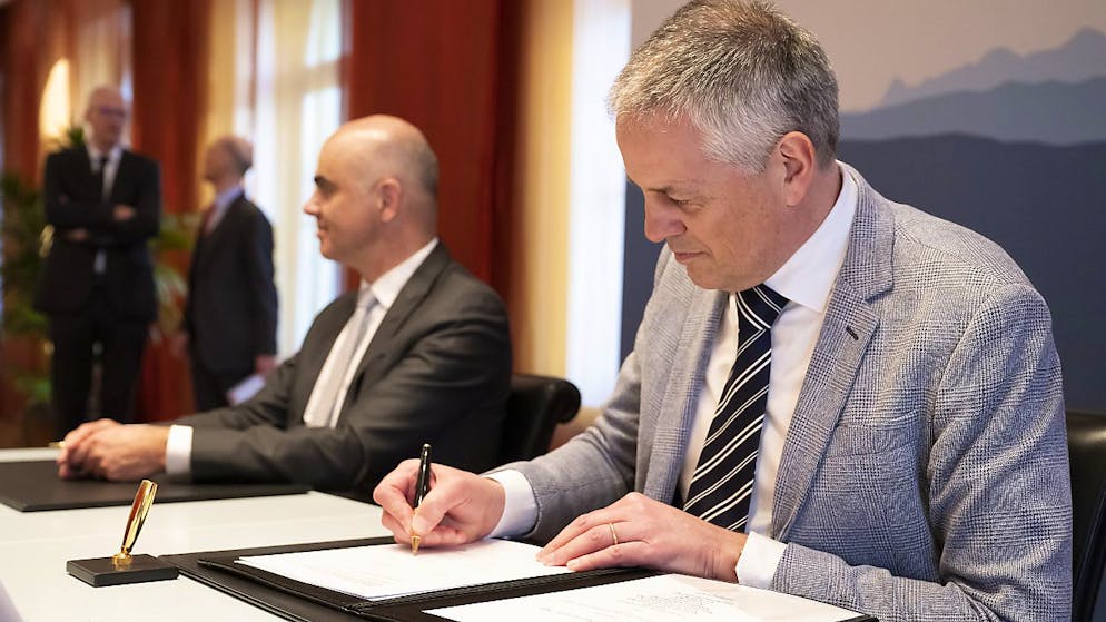 Erland Brügger, Geschäftsleiter der Gruppe Rivella (rechts), unterzeichnet ein Dokument, das seine Firma verpflichtet, den Zuckergehalt in Erfrischungsgetränken zu reduzieren.