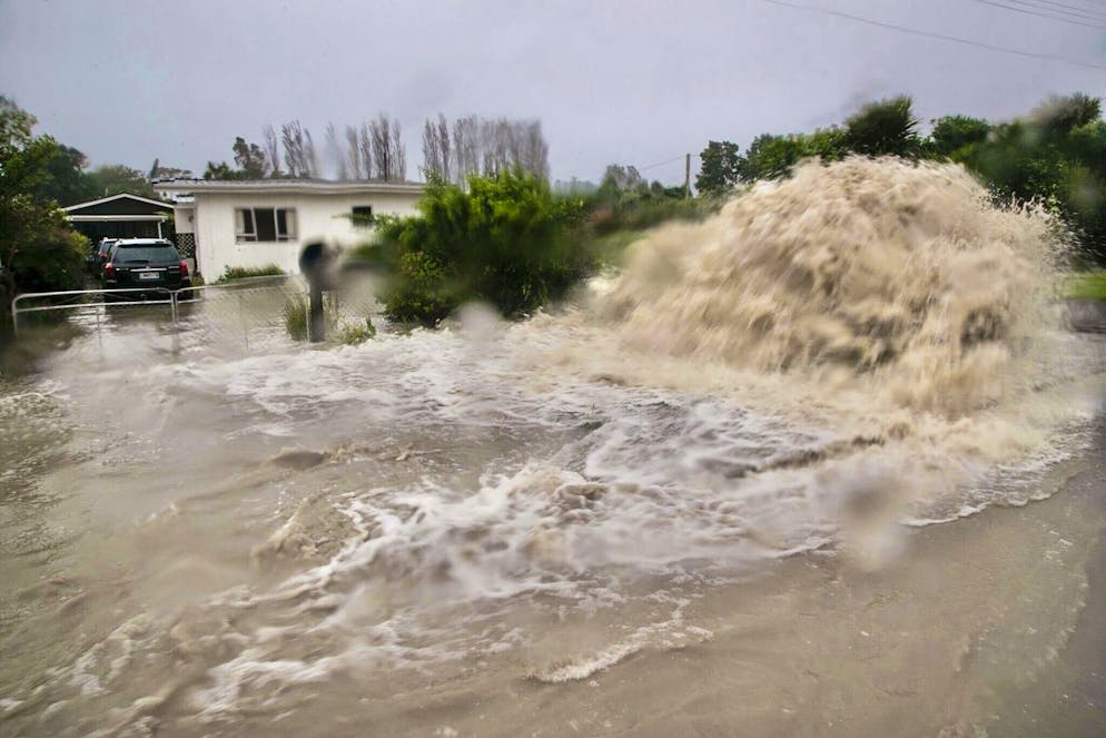 L'eau jaillit d'un port d'accès aux égouts pluviaux dans une rue de Te Awanga, au sud-ouest d'Auckland, en Nouvelle-Zélande, le mardi 14 février 2023. 