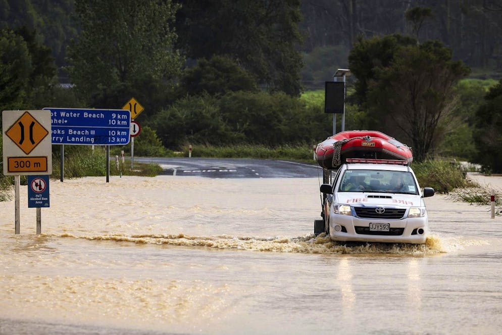 Un véhicule d'urgence transporte un bateau gonflable sur une route inondée à Cook's Beach, à l'est d'Auckland, en Nouvelle-Zélande, le mardi 14 février 2023.