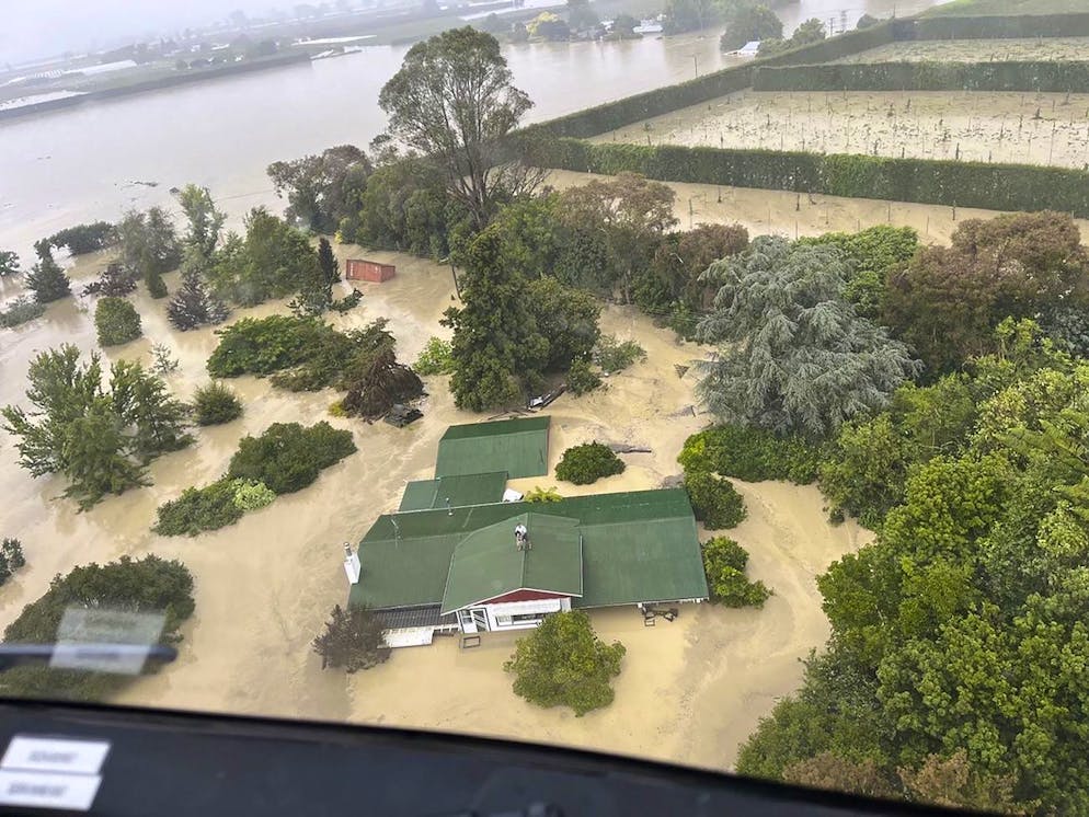 Dans cette image publiée par les Forces de défense néo-zélandaises le mercredi 15 février 2023, des personnes se tiennent sur le toit d'une maison attendant d'être treuillées en toute sécurité par hélicoptère dans la vallée d'Esk, près de Napier, en Nouvelle-Zélande.