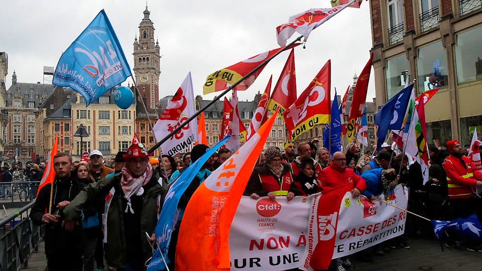 Demonstranten marschieren durch die Straßen und schwenken Fahnen während einer Demonstration gegen die geplante Rentenreform. Foto: Michel Spingler/AP/dpa