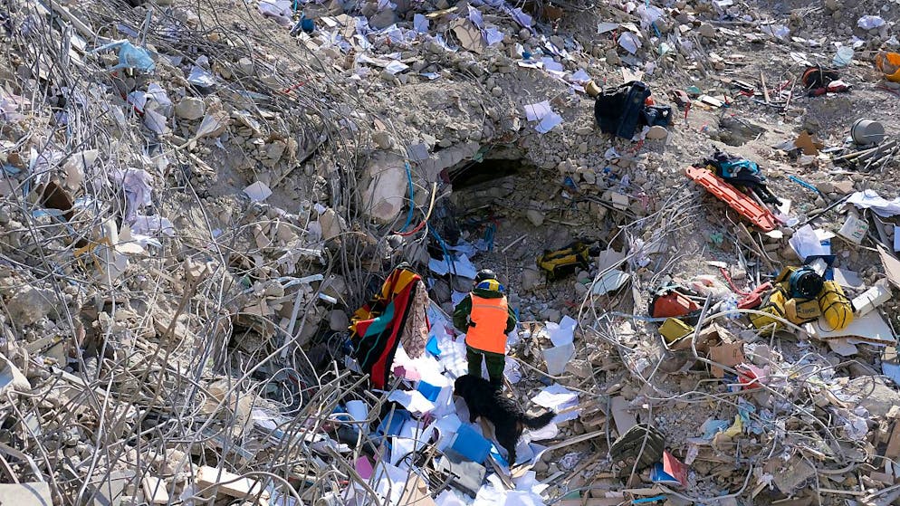 Ein Mann geht mit seinem Hund zwischen den Trümmern eines eingestürzten Gebäudes in Antakya. Foto: -/AP/dpa