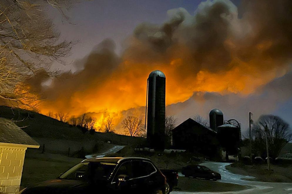 In this photo provided by Melissa Smith, a train fire is seen from her farm in East Palestine, Ohio, Friday, Feb. 3, 2023. A train derailment and resulting large fire prompted an evacuation order in the Ohio village near the Pennsylvania state line on Friday night, covering the area in billows of smoke lit orange by the flames below. (Melissa Smith via AP)