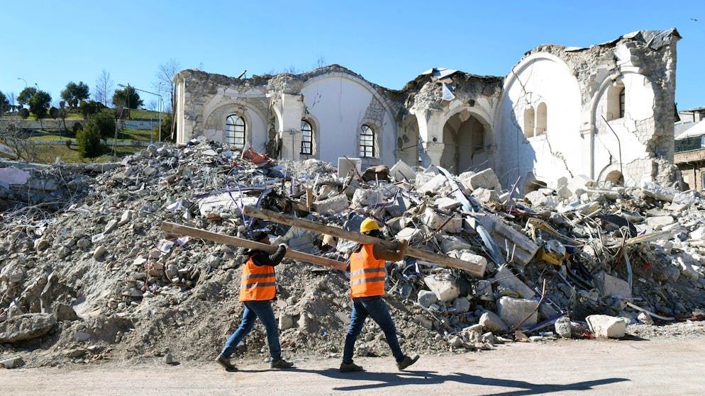 Mehr als 46.000 Tote – viele Schulen in Syrien zerstört - Gallery. Helfer gehen in Adiyaman an Trümmern vorbei.