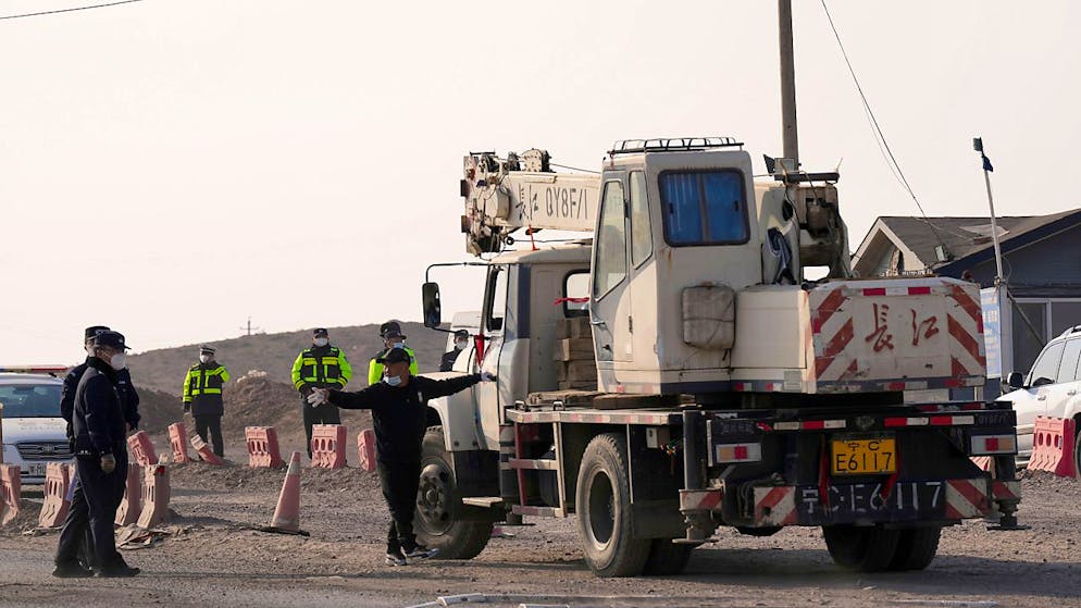 Ein Lastwagen wird  an einem Kontrollpunkt entlang einer Straße angehalten, die zum Ort eines eingestürzten Tagebaus in der Liga Alxa führt. Nach dem schweren Grubenunglück ist die Zahl der Todesopfer weiter gestiegen. Sechs Menschen konnten bisher lebend aus den Trümmern gerettet werden. 48 Bergleute werden aber noch vermisst. Foto: Ng Han Guan/AP/dpa