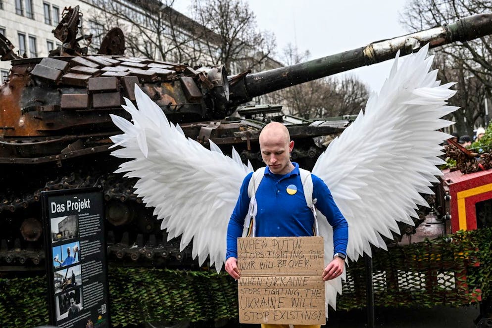 Un militant de la paix devant l'épave d'un char russe T-72, détruit en Ukraine et installé devant l'ambassade de Russie lors du premier anniversaire de l'invasion russe de l'Ukraine à Berlin, Allemagne, le 24 février 2023. 
