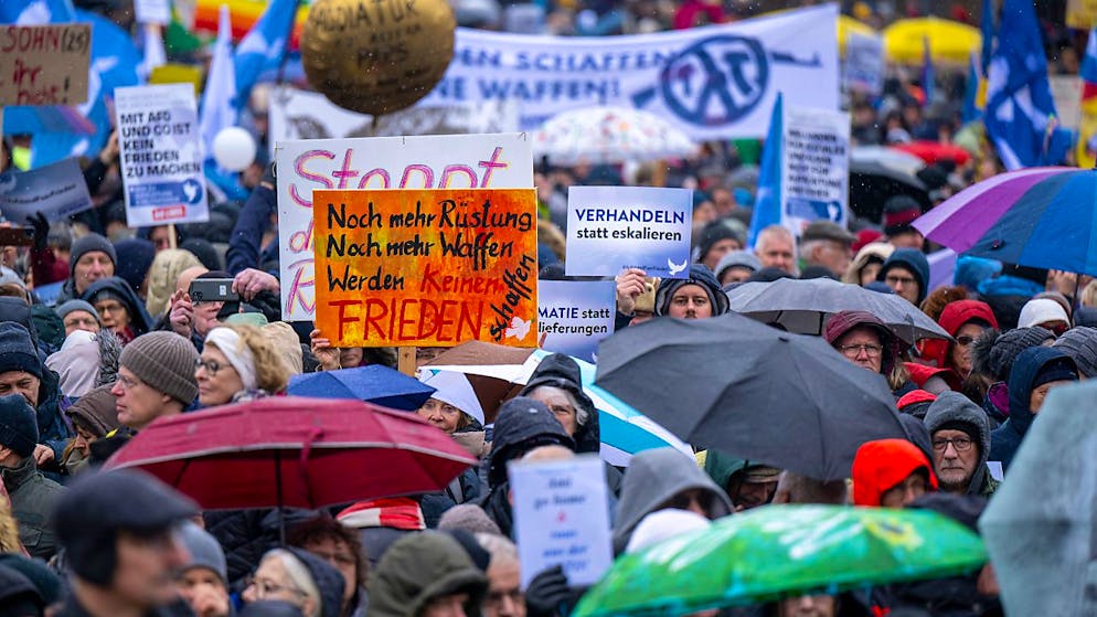 Zahlreiche Teilnehmer der Demonstration halten Schilder und Transparente in die Höhe. Am Brandenburger Tor in Berlin haben sich mehrere Tausend Menschen zu einer Kundgebung für Verhandlungen mit Russland im Ukraine-Krieg versammelt. Foto: Monika Skolimowska/dpa