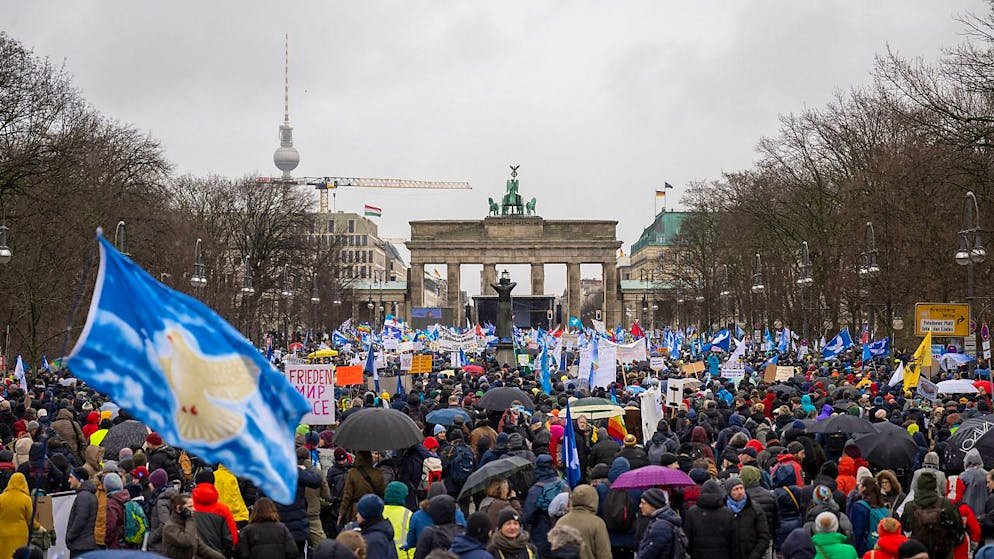 Teilnehmer einer Demonstration für Verhandlungen mit Russland stehen vor dem Brandenburger Tor. Foto: Christophe Gateau/dpa