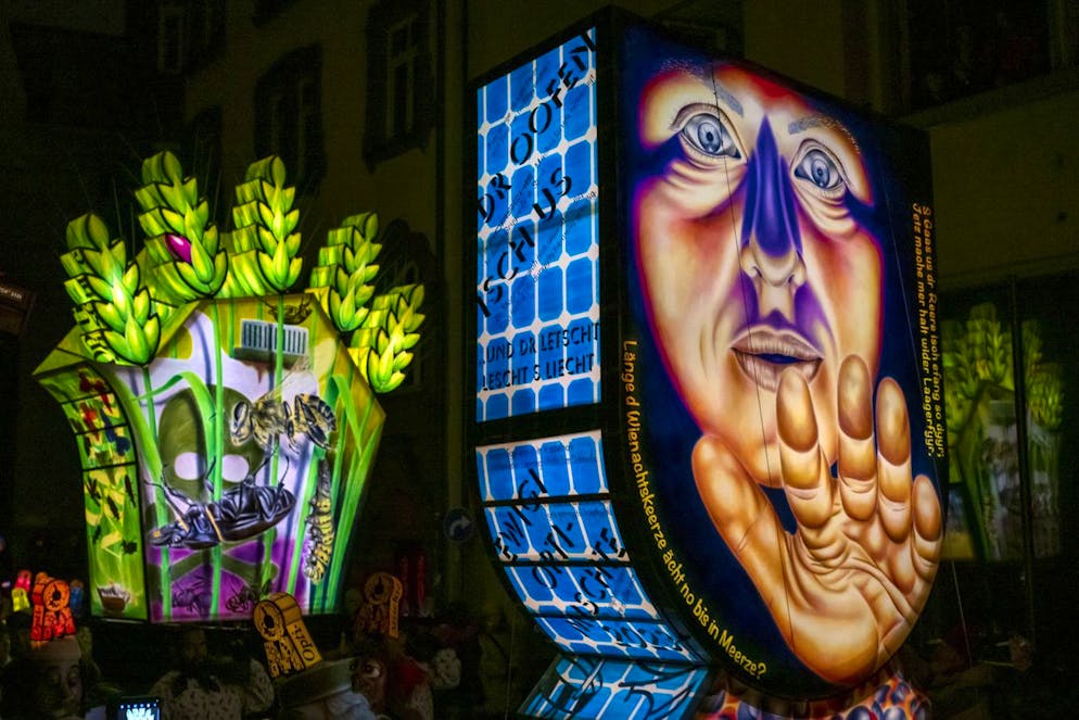 Basler Morgenstraich 2023. Fasnachtscliquen ziehen jeweils eine grosse Zuglaterne auf einem Wagen. Damit die Sujets auf den Laternen richtig zur Geltung kommen, wird die Strassenbeleuchtung gelöscht. 