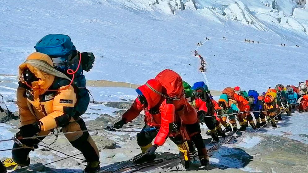 In einer langer Schlange klettern Bergsteiger auf einem Pfad knapp unterhalb von Lager vier.