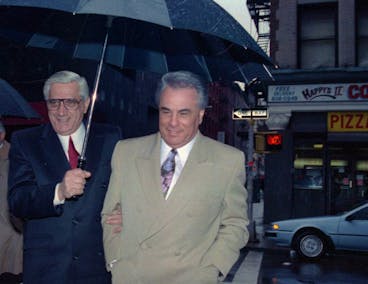 ** FILE ** Mobster John Gotti is shielded from rain by Anthony Guerrieri, Gotti's co-defendant in an assault and conspiracy trial, as they arrive at New York State Supreme Court in Manhattan, Jan. 22, 1990. Gotti, who swaggered, schemed and murdered his way to the pinnacle of organized crime in America only to be toppled by secret FBI tapes and a turncoat mobster's testimony, died at a prison hospital Monday, June 10, 2002 while serving a life sentence, a law enforcement source told The Associated Press. He was 61. (AP Photo/Sergio Florez)