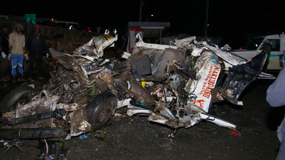 Menschen stehen nach dem tödlichen Unfall in Londiani in der Nähe der Fahrzeugwracks. 