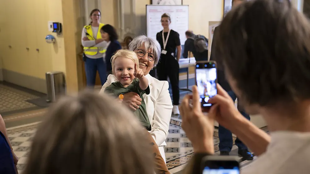 Lange Schlange vor dem Bundeshaus am Tag der offenen Bundesmeile - Gallery. Bundesrätin Elisabeth Baume-Schneider stellte sich den Fragen der Besucherinnen und Besucher und posierte für ein Foto mit einem Kind.