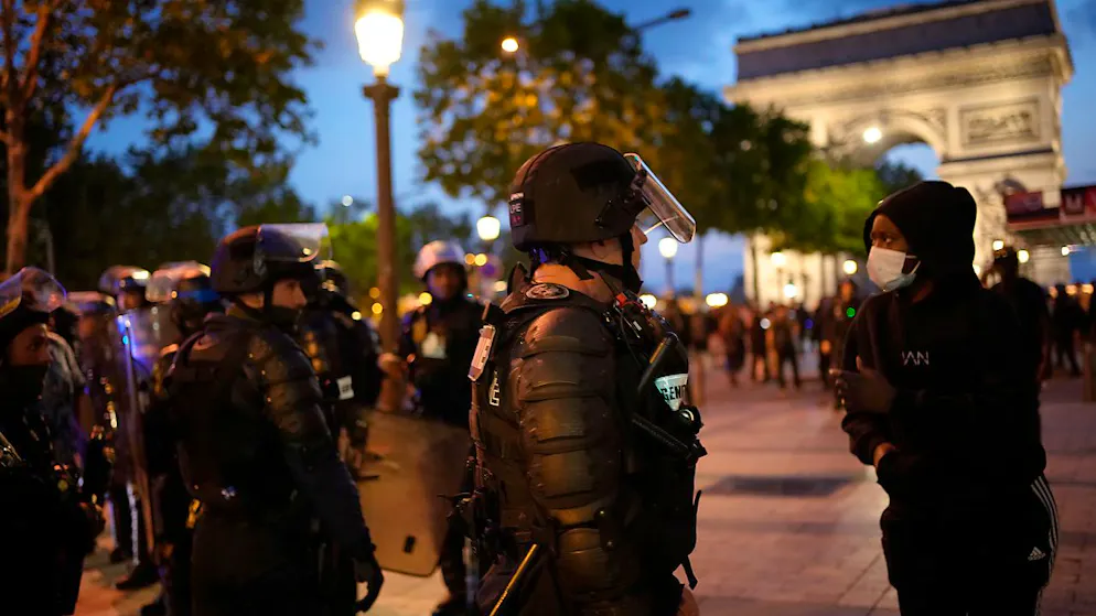 Polizisten sprechen mit einem Jugendlichen vor dem Arc de Triomphe auf den Champs Elysees. Foto: Christophe Ena/AP