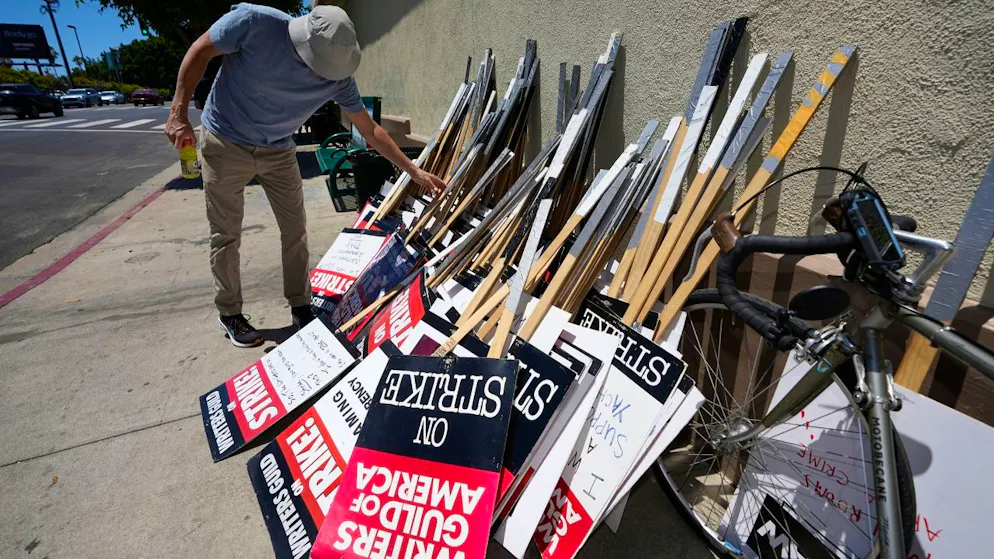 Ein Demonstrant wählt während einer Kundgebung der Writers Guild ein Protest-Schild aus. Schauspielerinnen und Schauspieler in den USA treten in den Streik. Foto: Mark J. Terrill/AP