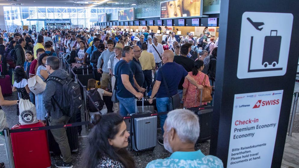 Menschen warten am 15. Juli 2023 vor dem Check-In Schalter am Flughafen in Zürich.