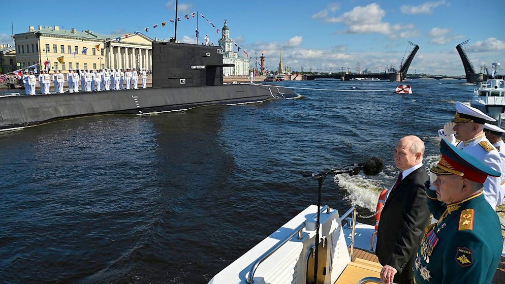 Wladimir Putin (l.) und sein Verteidigungsminister Sergej Schoigu (r.) sowie Admiral Nikolai Jewmenow (hinten) während der großen Marineparade zum Tag der Marine in St. Petersburg. Foto: Alexander Kazakov/Sputnik Kremlin/AP/dpa