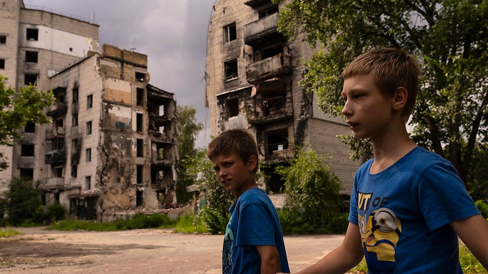 Zwei Jungs gehen in Borodjanka an Wohnhäusern vorbei, die bei Angriffen beschädigt wurden. Foto: Jae C. Hong/AP/dpa