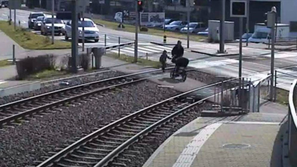 Die Barriere ist unten, eine erwachsene Person mit Kinderwagen und ein Kind überschreiten die Bahngleise: Gegen solche Gefahren startet Aargau Verkehr eine Sicherheitskampagne.