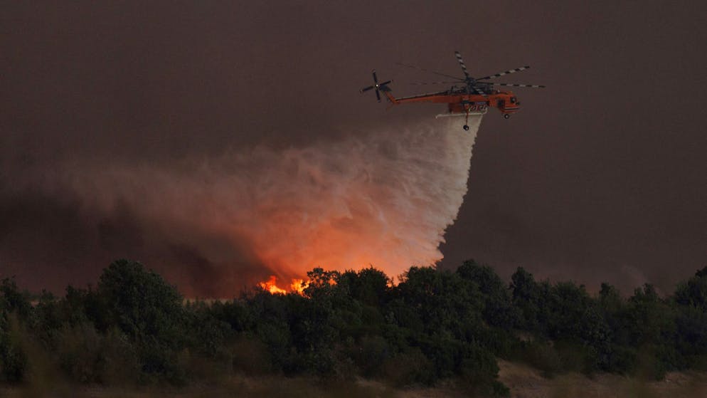 Waldbrände in Griechenland wüten weiter - Gallery. Ein Hubschrauber wirft Wasser über dem Dorf Avantas ab. Stürmische Winde fachen die Flammen der Waldbrände in ganz Griechenland an.