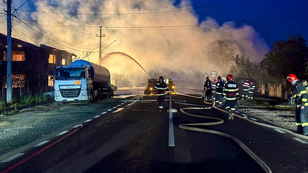 Feuerwehrleute bei Löscharbeiten nach einer Explosion an einer Tankstelle für Flüssiggas (LPG).