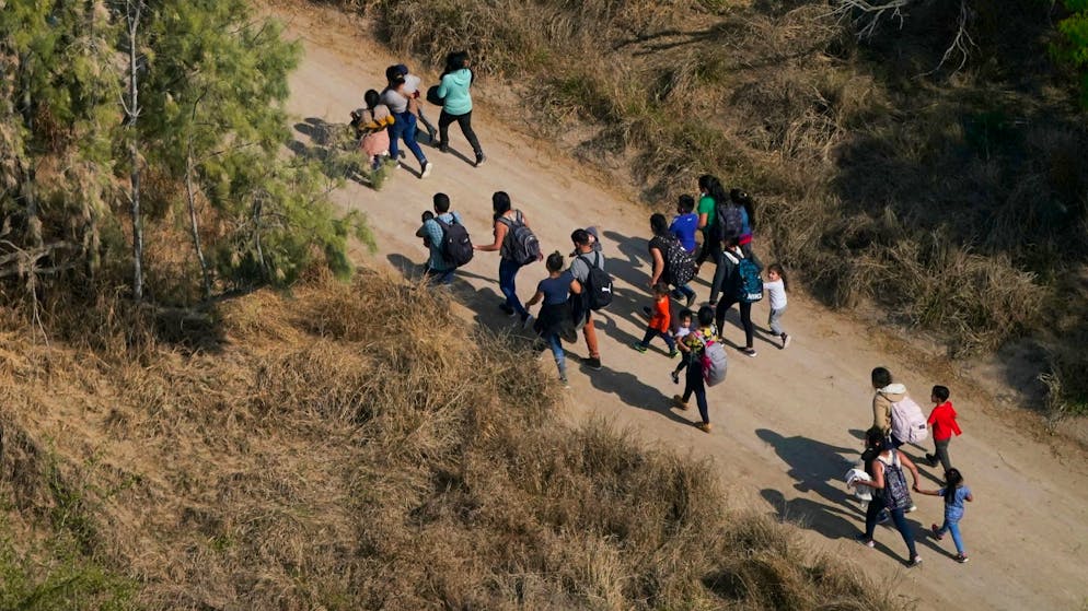 Migranten gehen einen Feldweg entlang, nachdem sie die Grenze zwischen den USA und Mexiko überquert haben.