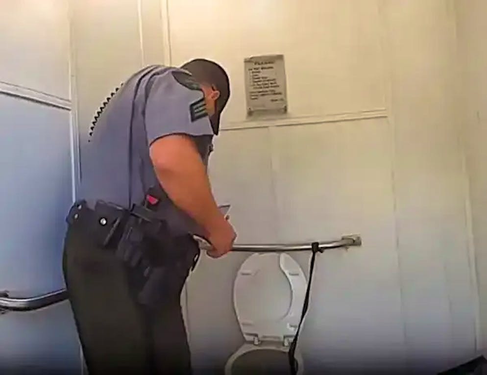 Un agente di polizia guarda il wc su cui era salita una donna.  