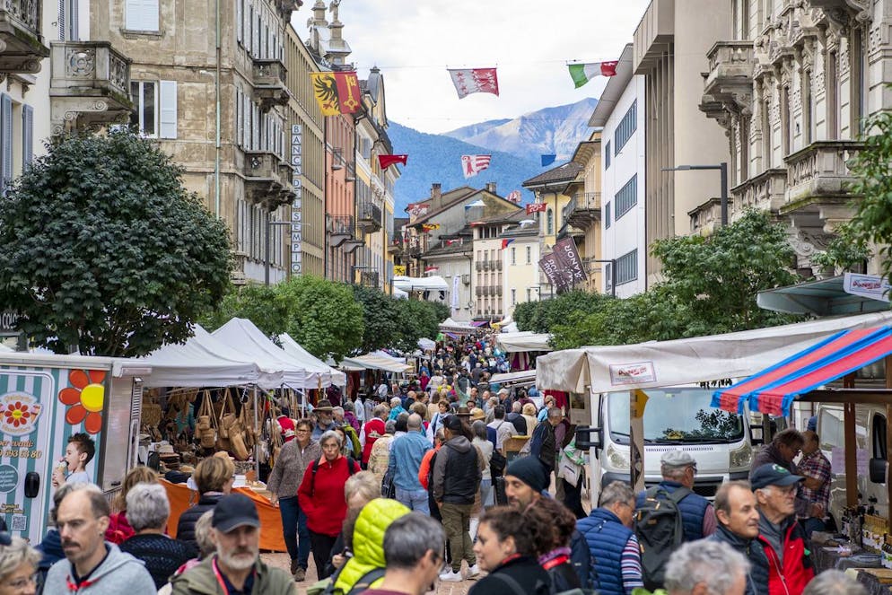 La gente passeggia al mercato del Festival federale della musica popolare a Bellinzona nel centro storico della città.