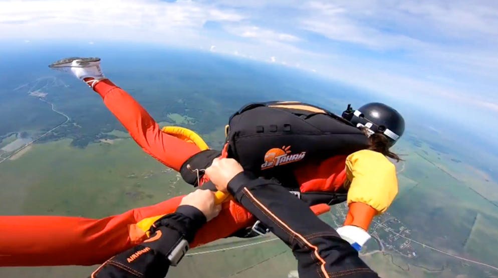 L'istruttore riesce, non senza una qualche difficoltà, prima a raggiungere l'allieva e poi ad aprirle il paracadute.