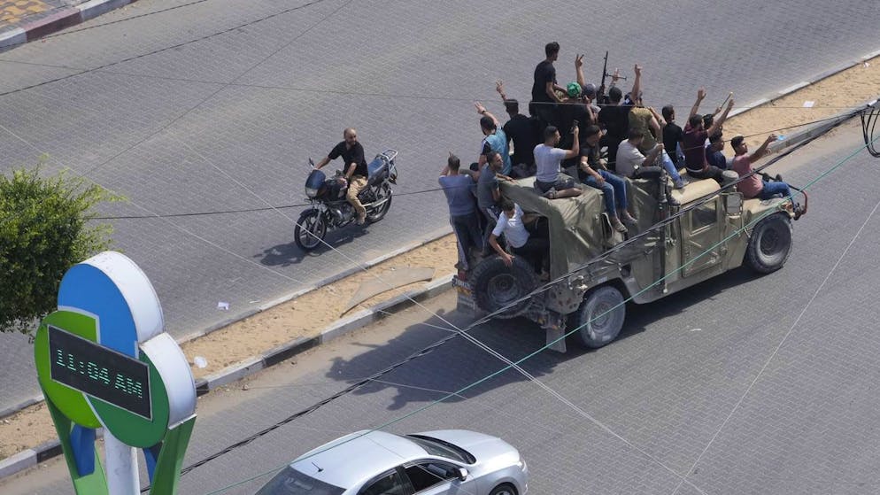 Militante Hamas-Kämpfer fahren in einem erbeuteten israelischen Militärfahrzeug durch Gaza-Stadt.