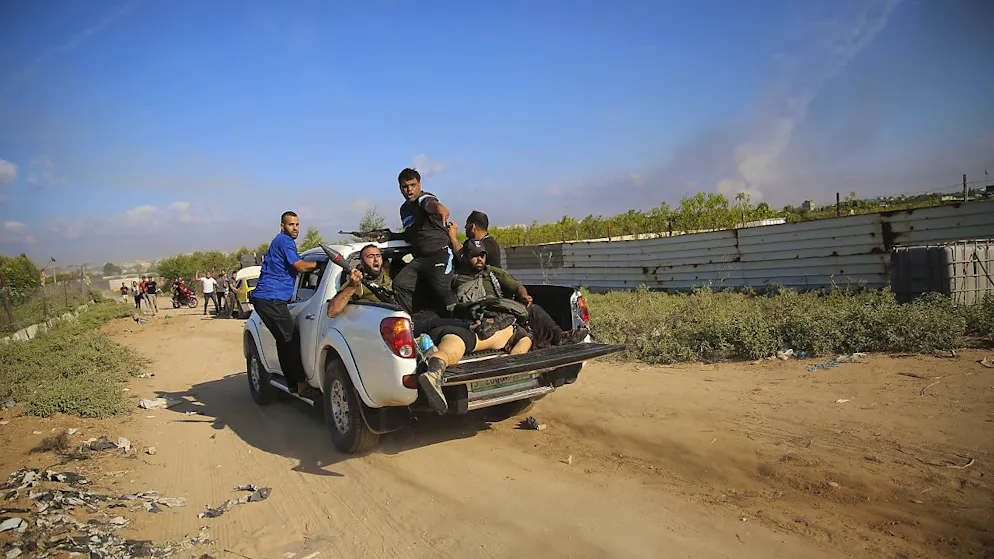 Miliziani palestinesi fanno rientro a Gaza con il corpo di un civile, dopo l'attacco in territorio israeliano.