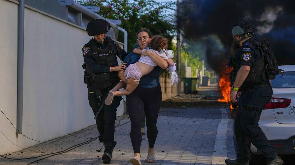 Eine Frau wird nach den Angriffen der Hamas auf Israel in Sicherheit gebracht: Wegen des koordinierten Vorgehens und Ausrüstung der islamistische Terrororganisation vermuten Experten Unterstützung aus dem Iran.