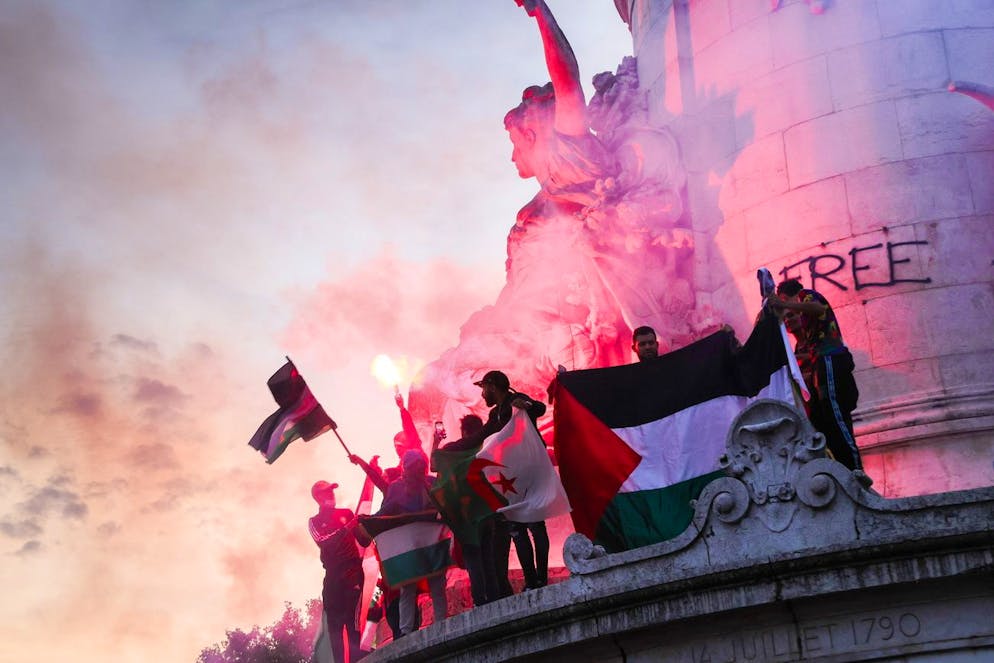 Alcune persone con bandiere di diversi Paesi arabi a una dimostrazione vietata in supporto della popolazione palestinese a Parigi.  