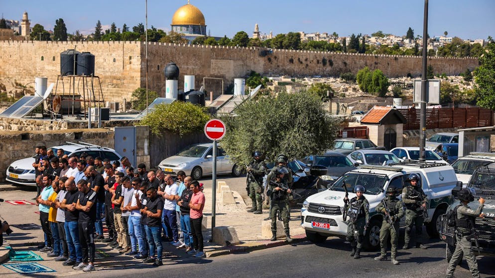 مصلون فلسطينيون يصلون بينما تحرس القوات الإسرائيلية خارج البلدة القديمة في القدس.  (صورة أرشيفية)