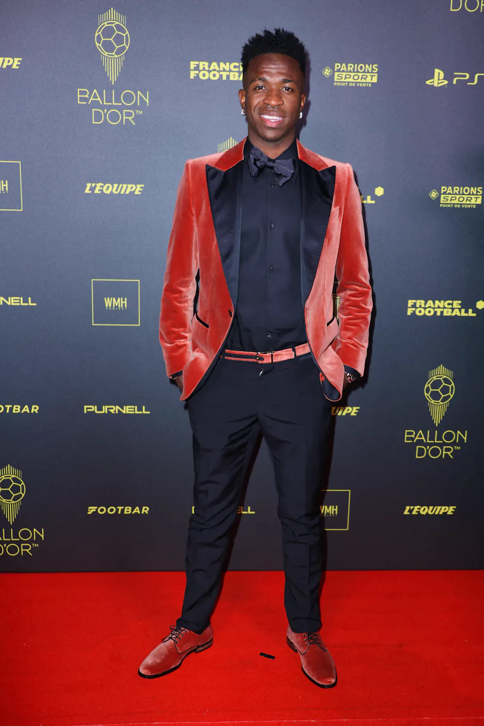 Les looks du tapis rouge du Ballon d'Or 2023. Vinicius Jr. a reçu le prix Socrates pour son engagement en faveur des enfants défavorisés à travers sa fondation. Question mode, il a osé sur le tapis rouge. Sa tenue était frappante car il avait choisi un blazer en velours rouge avec des revers noirs et un col pointu, auquel il avait associé un pantalon noir et une chemise noire. Ses chaussures lacées étaient assorties à son blazer ainsi qu'à sa ceinture. Le fait qu’il ait choisi le rouge n’est certainement pas une coïncidence, car c’est après tout la couleur dominante de l’automne-hiver 2023/24.