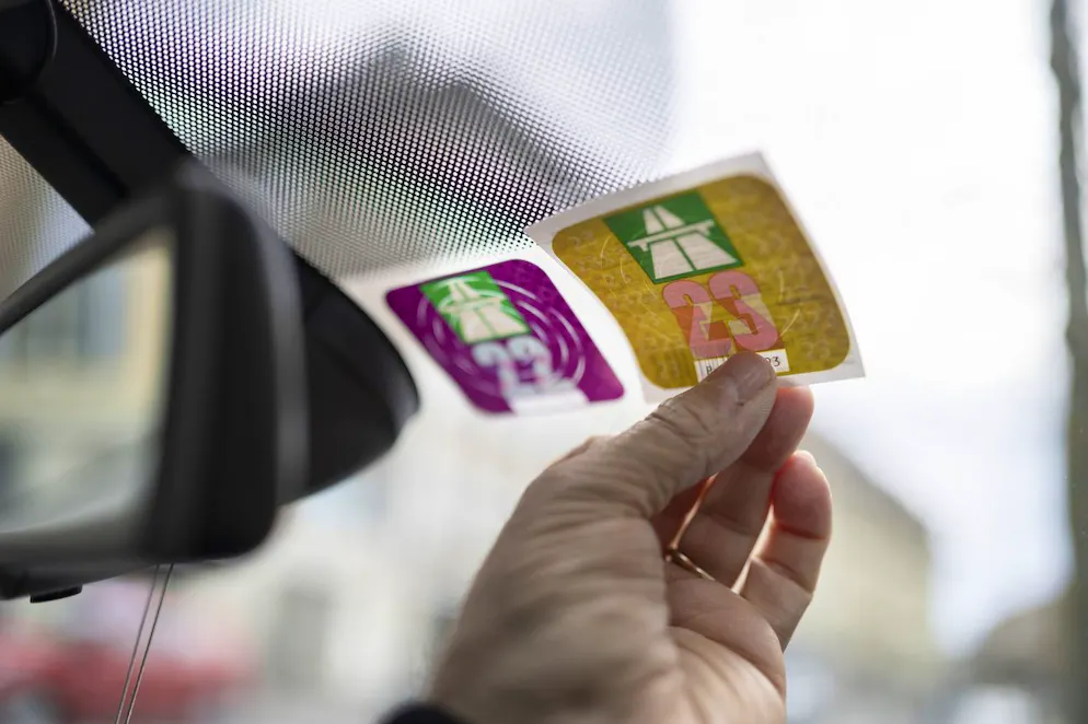 Ein Mann hält eine Schweizer Autobahnvignette für das Jahr 2023 neben diejenige des Jahres 2022, fotografiert am Donnerstag, 12. Januar 2023 in Bern. (Keystone/Christian Beutler)
