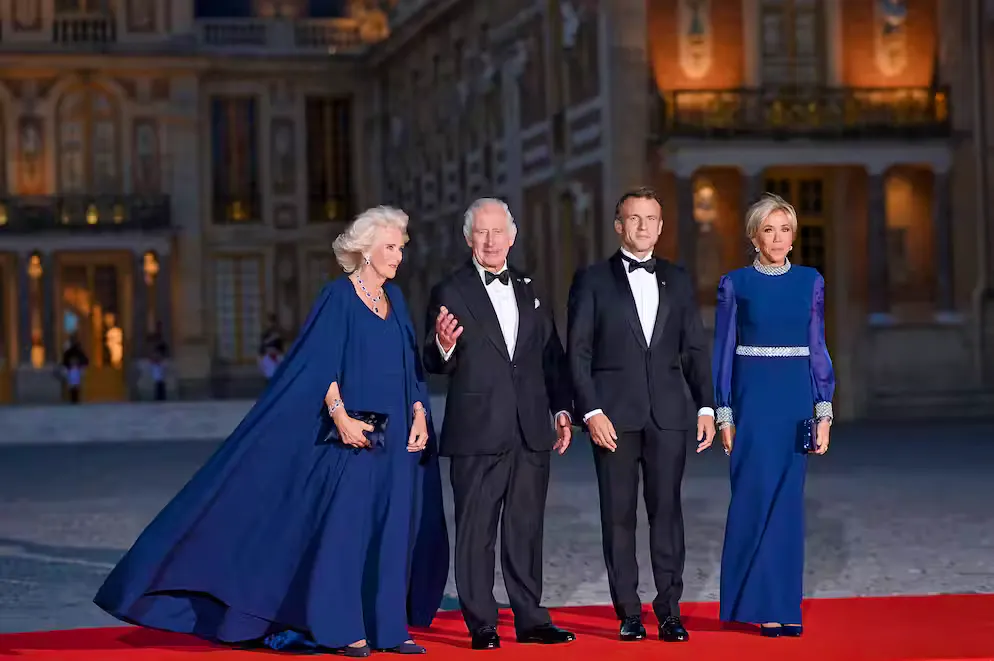 La «robe cape» de Kate. La robe-cape a également frappé fort le 20 septembre, alors que le couple présidentiel avait organisé un dîner d'État à Versailles. La reine Camilla arborait une robe cape en crêpe de soie qui flottait majestueusement au vent. 