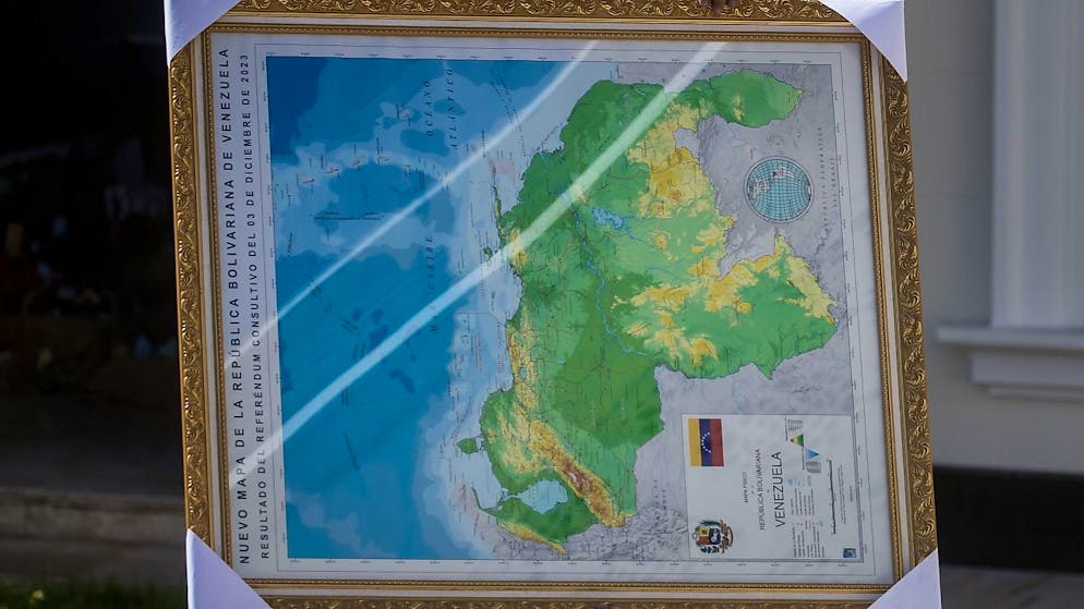 Un uomo trasporta porta una cartina del Venezuela con annesso il territorio dell'Esequibo nei giardini del parlamento di Caracas.